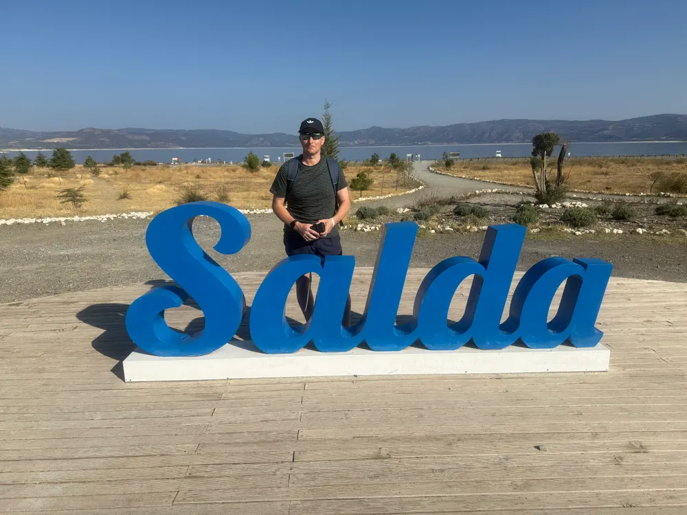 Mark Burtenshaw standing behind a large blue Salda sign with the lake behind him