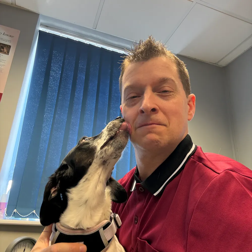 Mark Burtenshaw, director and principal accountant, getting a lick on the cheek from an office dog