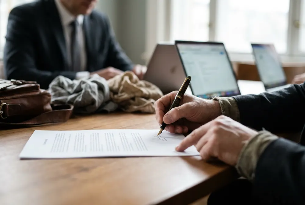 Client signing a letter of engagement with a pen at a meeting table